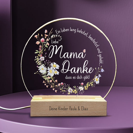 LED-Nachtlicht mit personalisierbarem Holzsockel und liebevollem Spruch für Mama: „Ein Leben lang behütet, beschützt und geliebt... Liebe Mama, Danke, dass es dich gibt!“. Die Acrylglasplatte ist mit einem zarten Blumenkranz verziert und wird von warmweißem LED-Licht beleuchtet. Ideal als Muttertagsgeschenk oder als besondere Aufmerksamkeit.