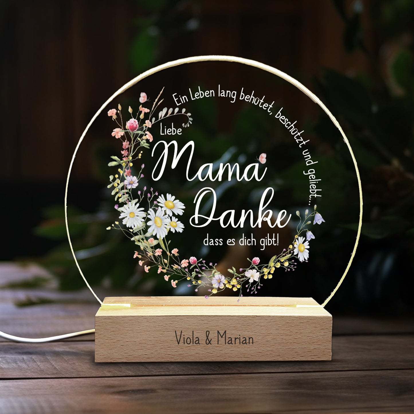 Personalisiertes LED-Nachtlicht für Mama mit filigranen Frühlingsblumen und dem Spruch „Ein Leben lang behütet, beschützt und geliebt... Liebe Mama, Danke, dass es dich gibt!“. Die Acrylplatte wird von einem warmweißen LED-Licht beleuchtet, der Holzsockel ist mit einer individuellen Gravur personalisierbar. Perfektes Geschenk zum Muttertag oder als liebevolle Aufmerksamkeit.