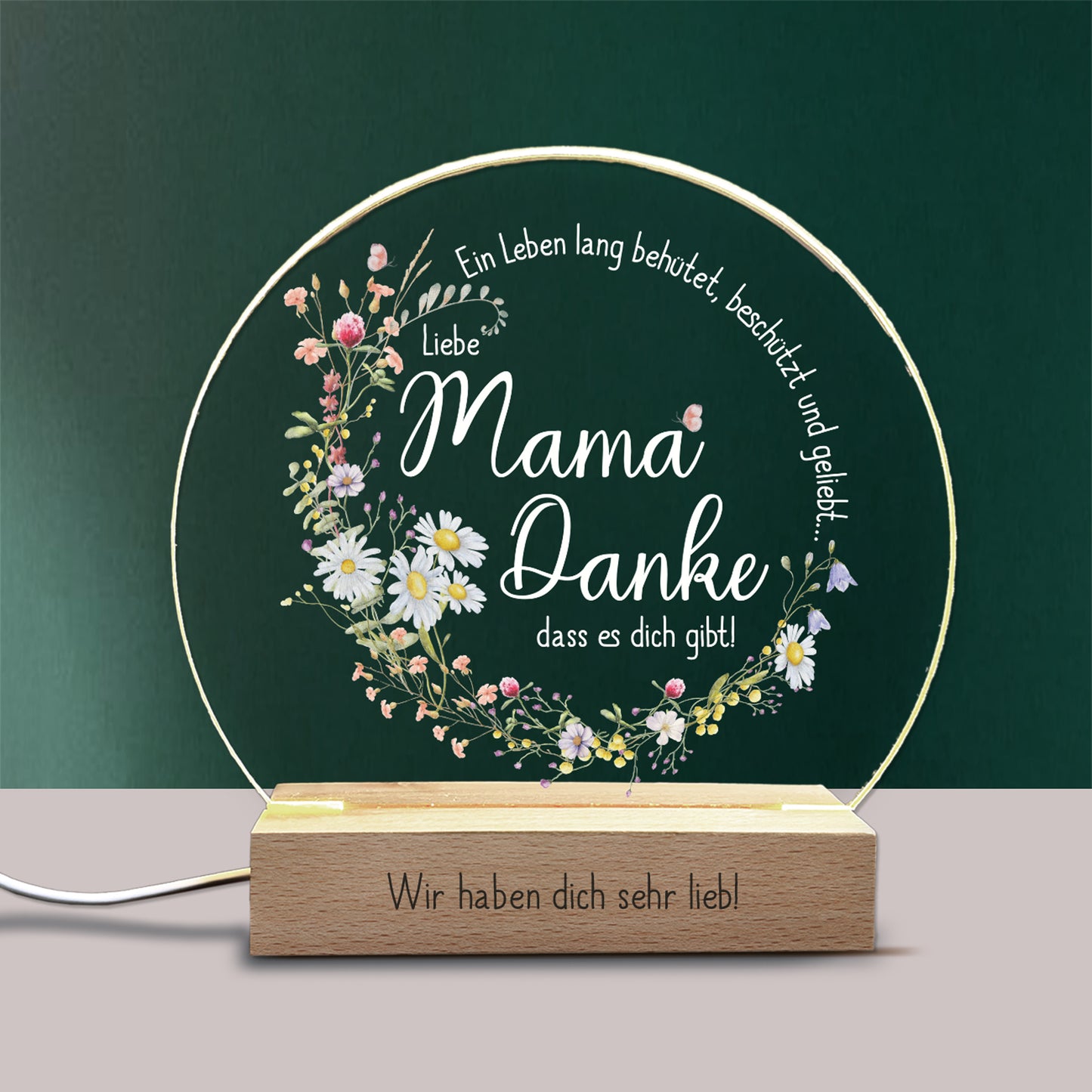 LED-Nachtlicht mit personalisierbarer Gravur auf dem Holzsockel, gestaltet als liebevolles Geschenk für Mama. Die Acrylplatte zeigt einen Kranz aus Frühlingsblumen mit dem Spruch „Ein Leben lang behütet, beschützt und geliebt... Liebe Mama, Danke, dass es dich gibt!“. Warmweißes LED-Licht sorgt für eine stimmungsvolle Beleuchtung – ideal als Muttertagsgeschenk oder liebevolle Überraschung.