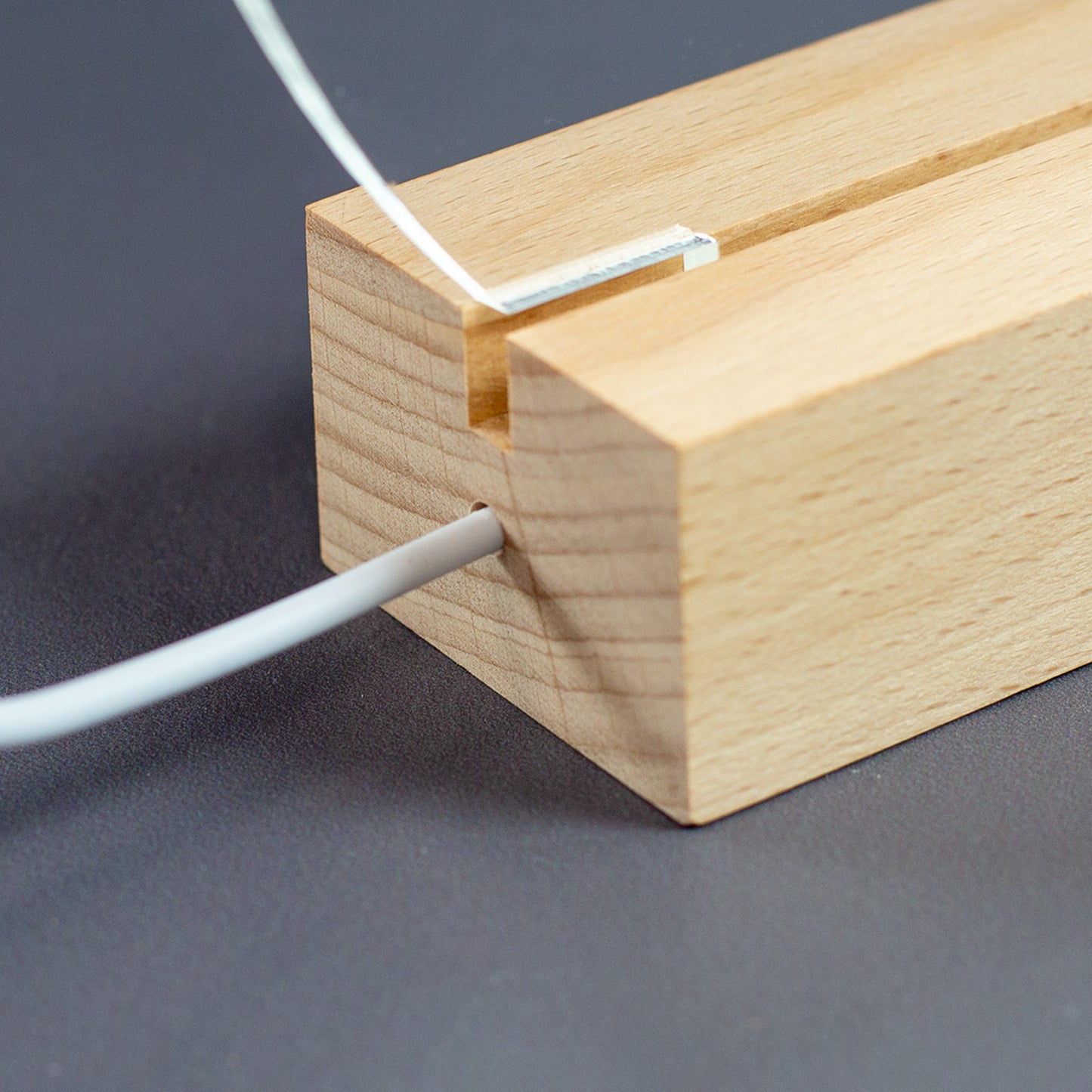 Detailaufnahme des Holzsockels mit eingelassener Acrylglasplatte und USB-Kabelanschluss