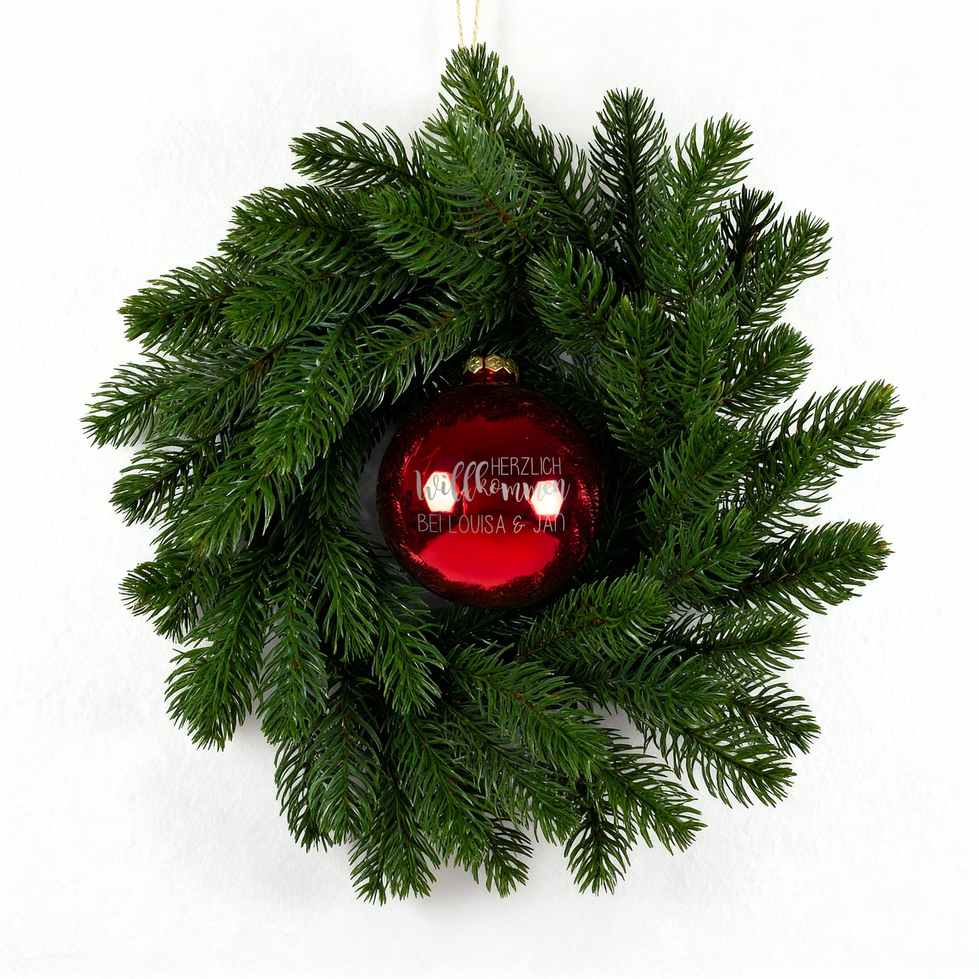 Weihnachts-Türkranz mit roter Kugel „Herzlich willkommen“ auf weißem Hintergrund