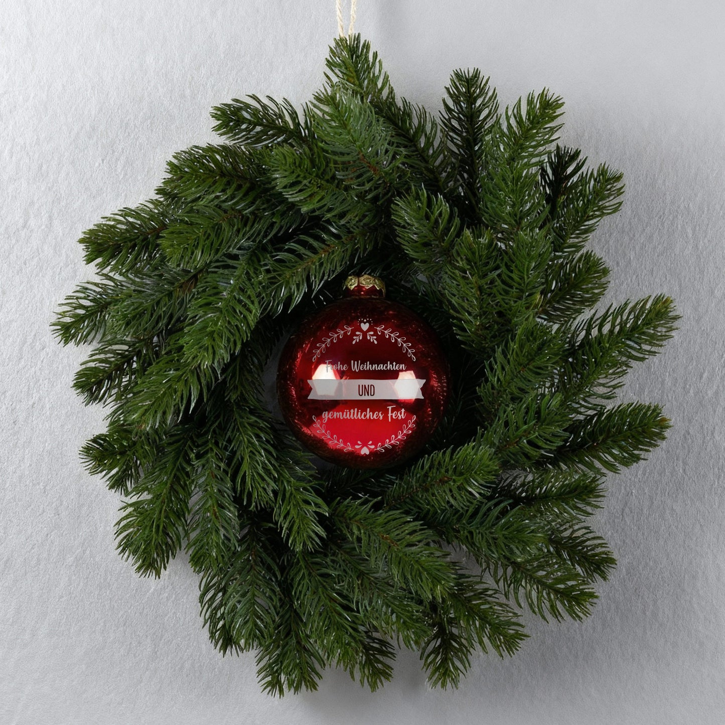 Türkranz an grauer Wand mit roter gravierter Weihnachtskugel