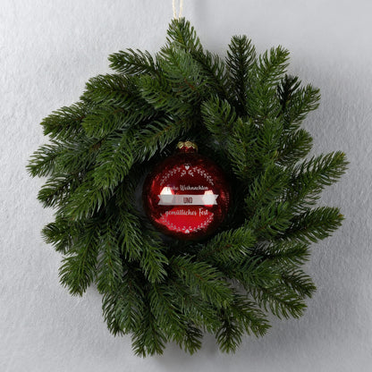 Türkranz an grauer Wand mit roter gravierter Weihnachtskugel