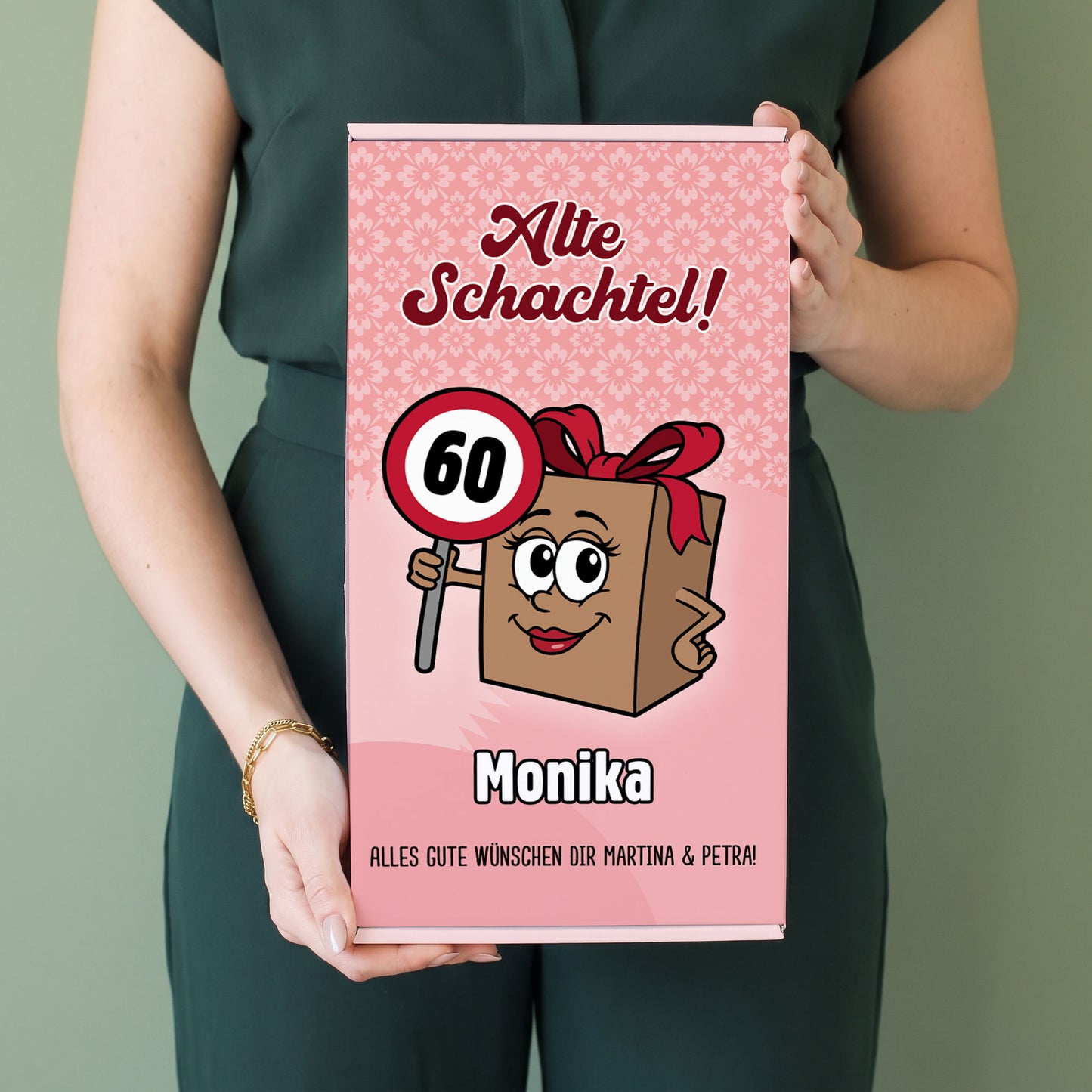 Frau hält personalisierte Geschenkbox „Alte Schachtel!“ mit Name Monika und Alter 60 in den Händen
