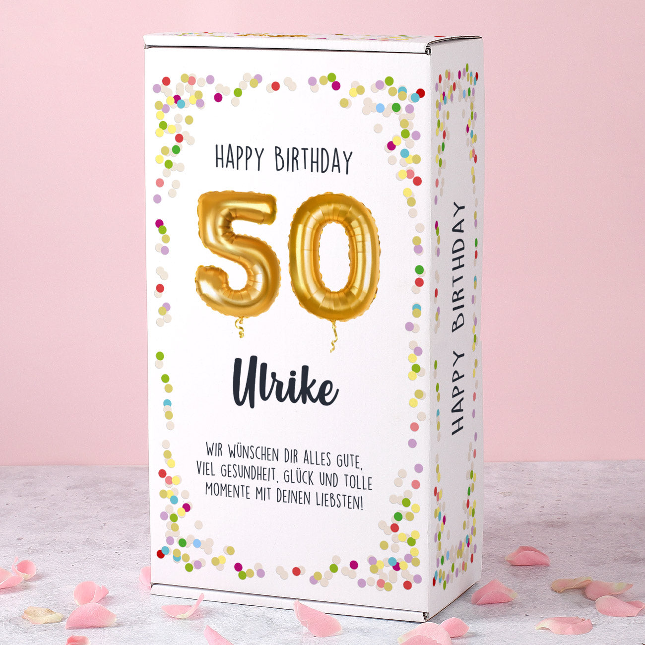 Weiße Geschenkbox mit goldenen Ballon-Zahlen „50“, Konfetti-Muster und personalisiertem Namen „Ulrike“.