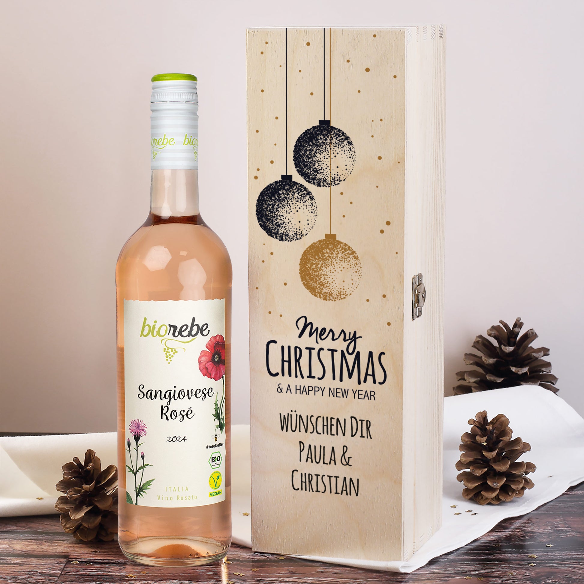 Flasche Biorebe Sangiovese Rosé mit gravierter Holzbox „Merry Christmas & a Happy New Year“, personalisiert mit „Paula & Christian“.