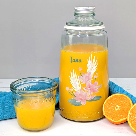 Karaffe auf einem Tisch gefüllt mit Saft - daneben Orangen