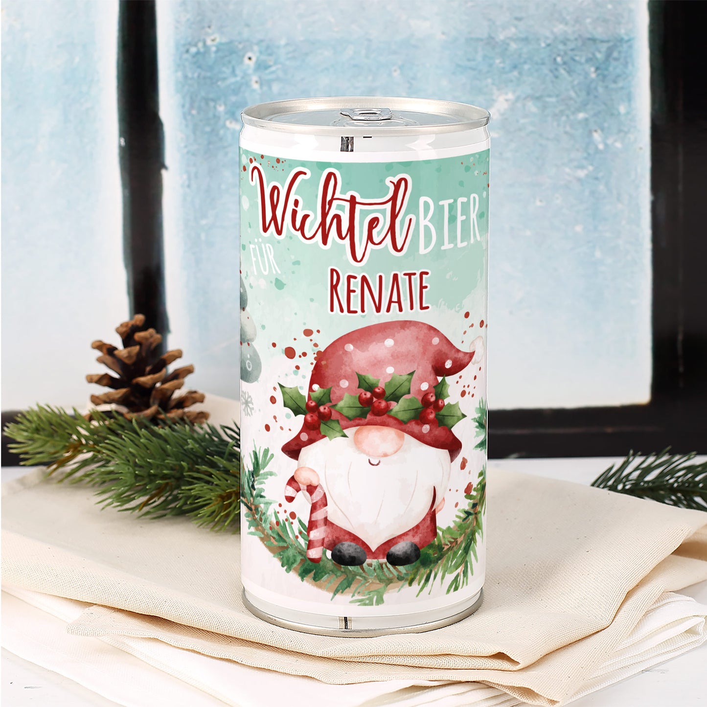 Wichtelbier-Dose mit personalisiertem Namen Renate vor winterlicher Fensterkulisse und weihnachtlicher Tannendeko.