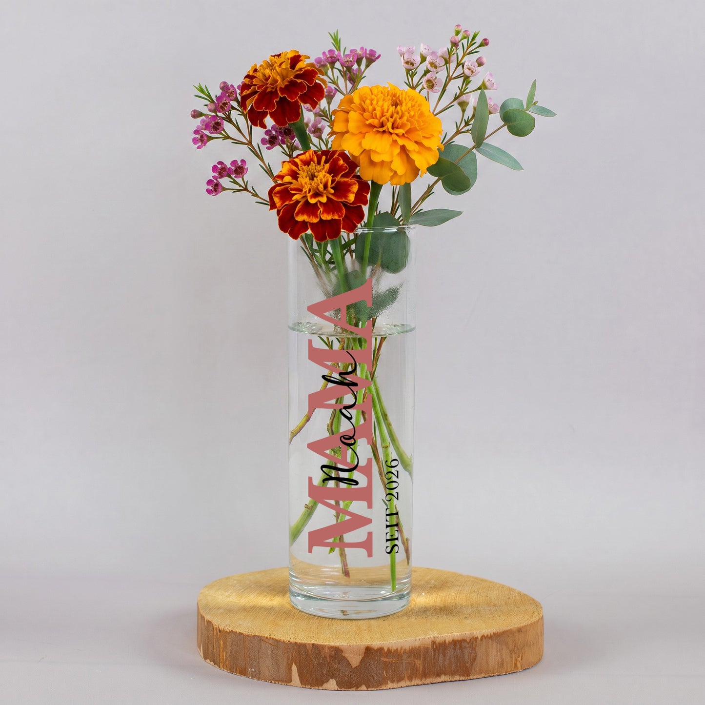 Personalisierte Mama Vase aus Glas mit Namen und Jahreszahl 2026, dekoriert mit orangefarbenen Blumen und Eukalyptus