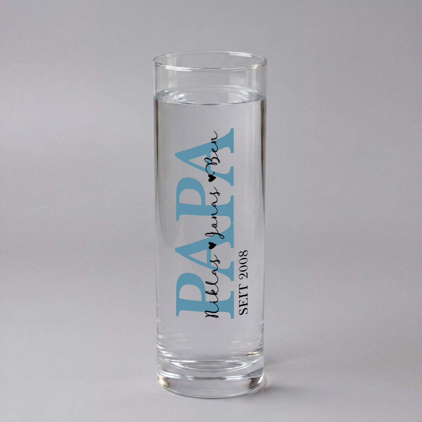 Personalisierte Papa Vase aus Glas mit blauem Schriftzug, Name und Jahreszahl 2022, dekoriert mit Frühlingsblumen auf Holzscheibe