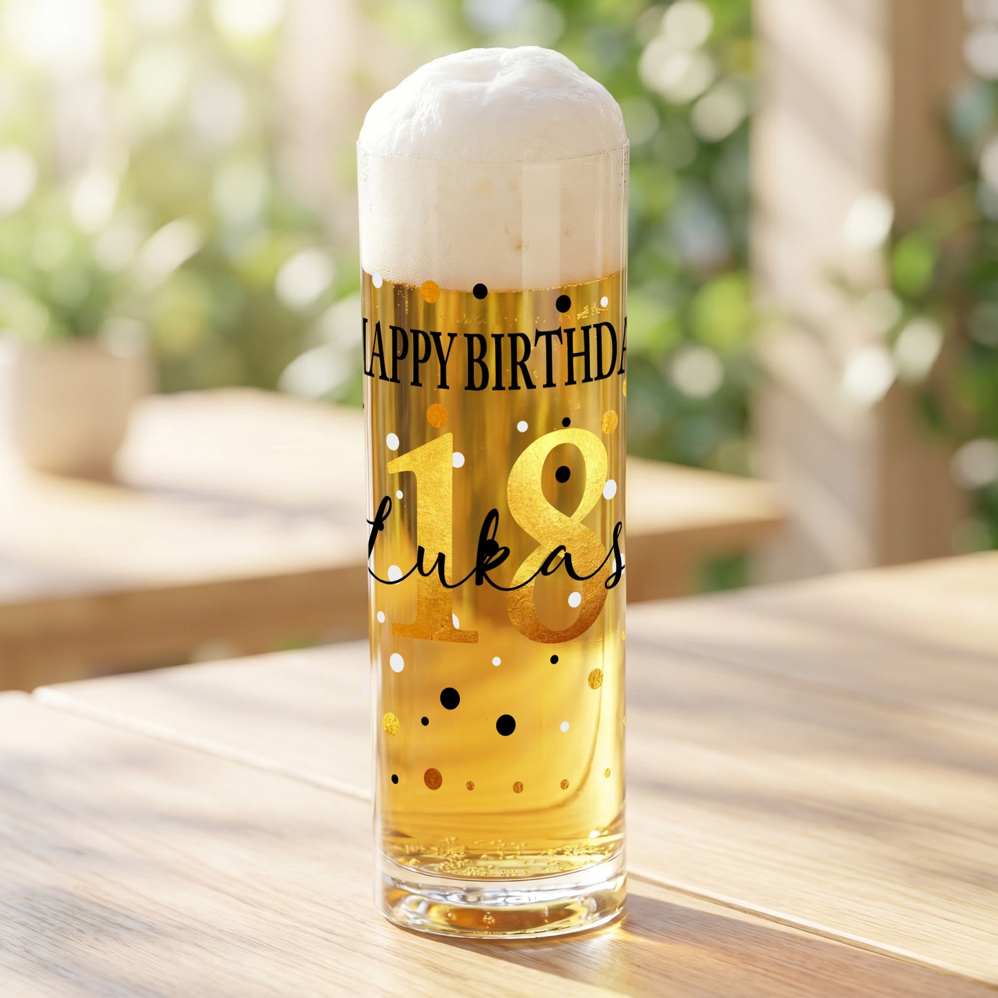 Personalisiertes Kölschglas mit Geburtstagsmotiv „Happy Birthday“, goldener Zahl 18 und dem Namen Lukas, gefüllt mit hellem Bier auf einem Holztisch im Außenbereich.