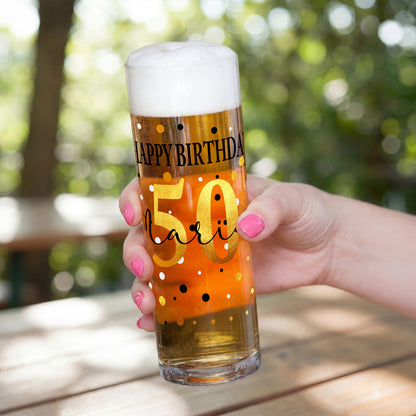 Geburtstags-Kölschglas mit großer goldener Zahl 50 und personalisiertem Namen, gehalten in einer Hand, gefüllt mit Bier und Schaum.