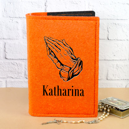 Personalisierte Filz Buchhülle in Orange mit betenden Händen und Name Katharina vor heller Wand
