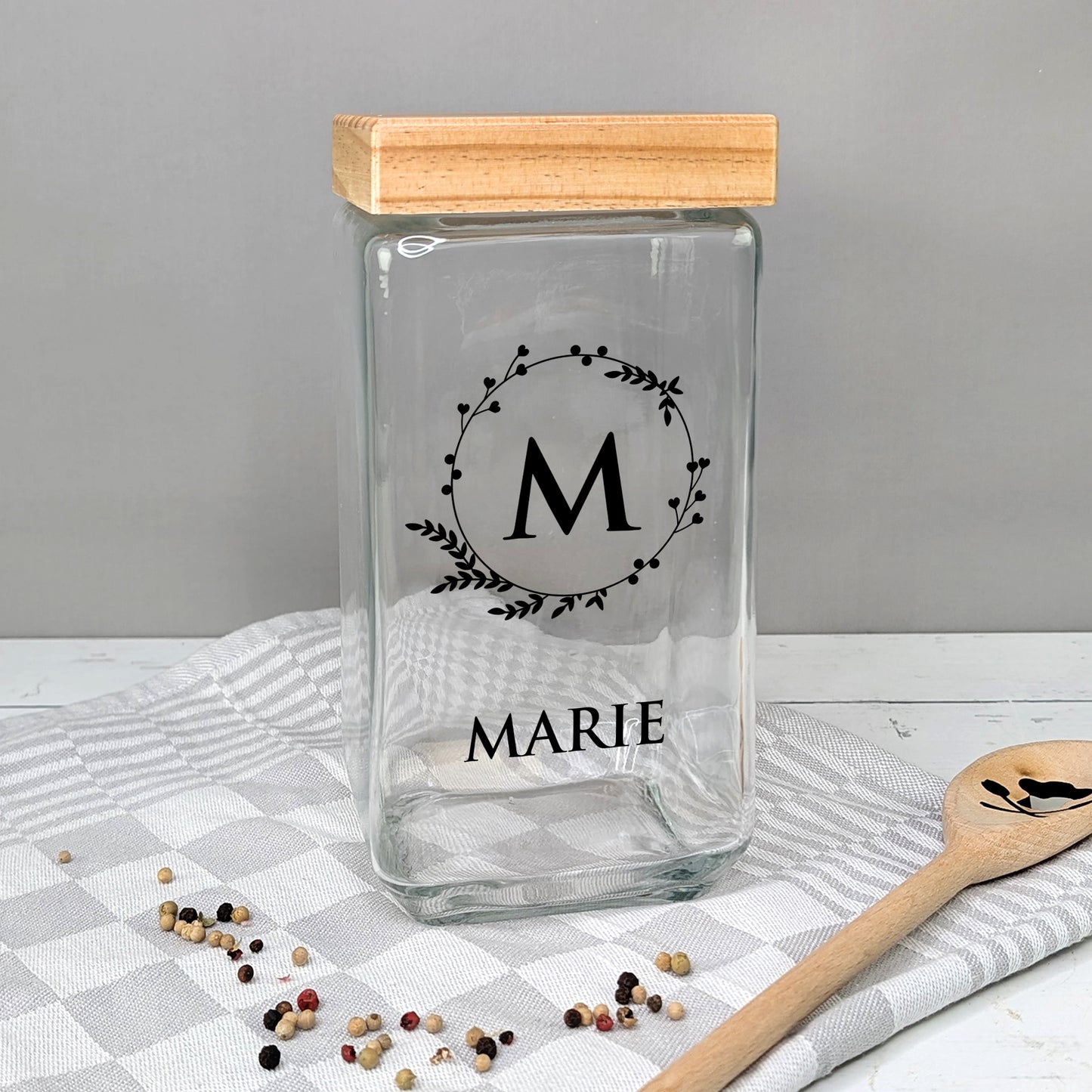 Glasvorratsbehälter mit Initiale „M“ und Name „MARIE“, auf Tisch mit Geschirrtuch, Variante in Schwarz