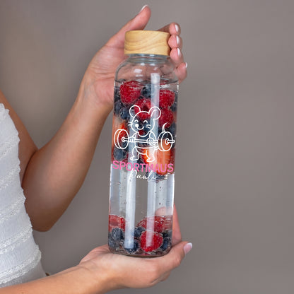 Glas Trinkflasche mit Sportmaus Motiv und Name, in Händen gehalten, gefüllt mit Beeren und Trinkhalm