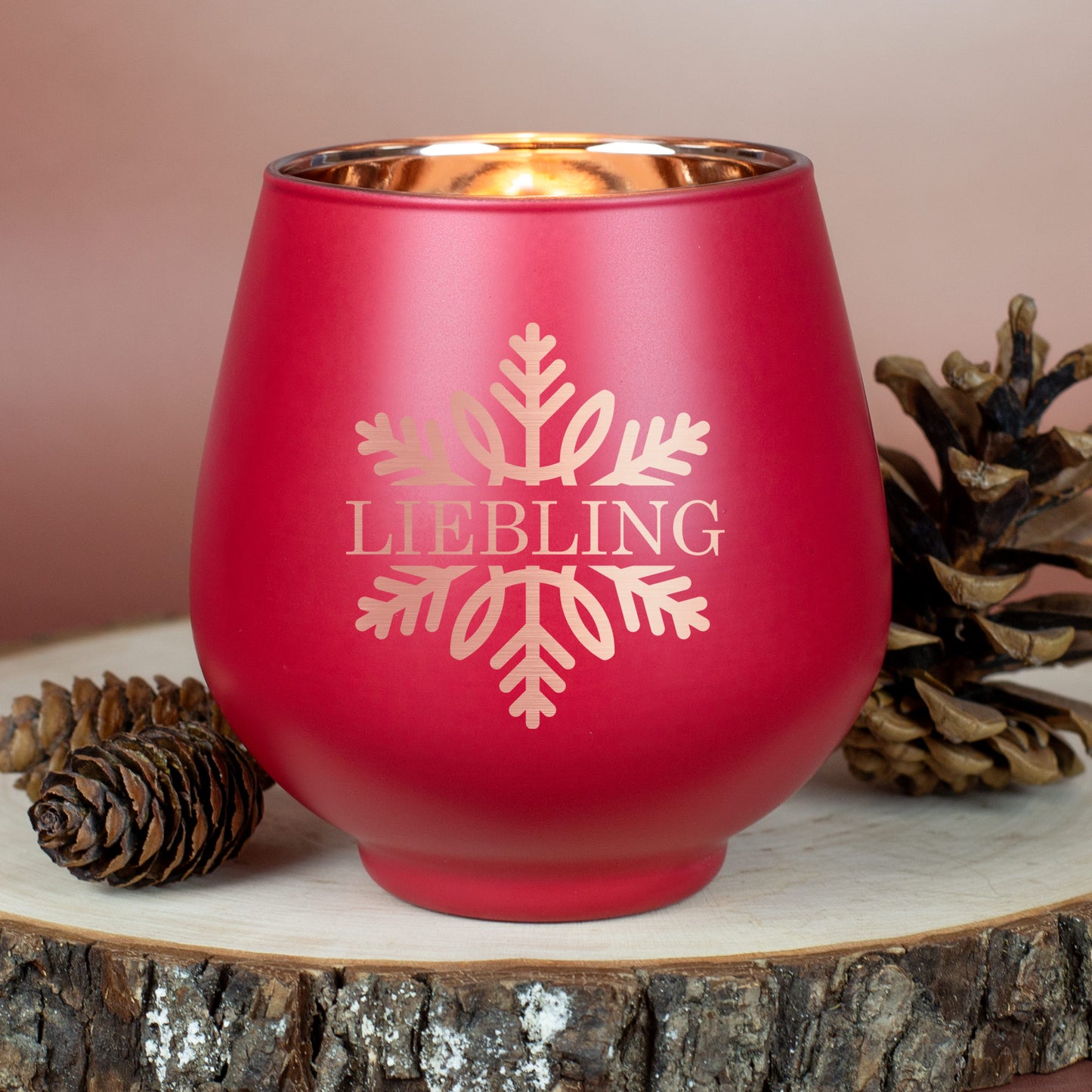 Rotes Windlicht mit Gravur „Liebling“ und Schneeflocke, auf Holzscheibe mit Zapfen platziert