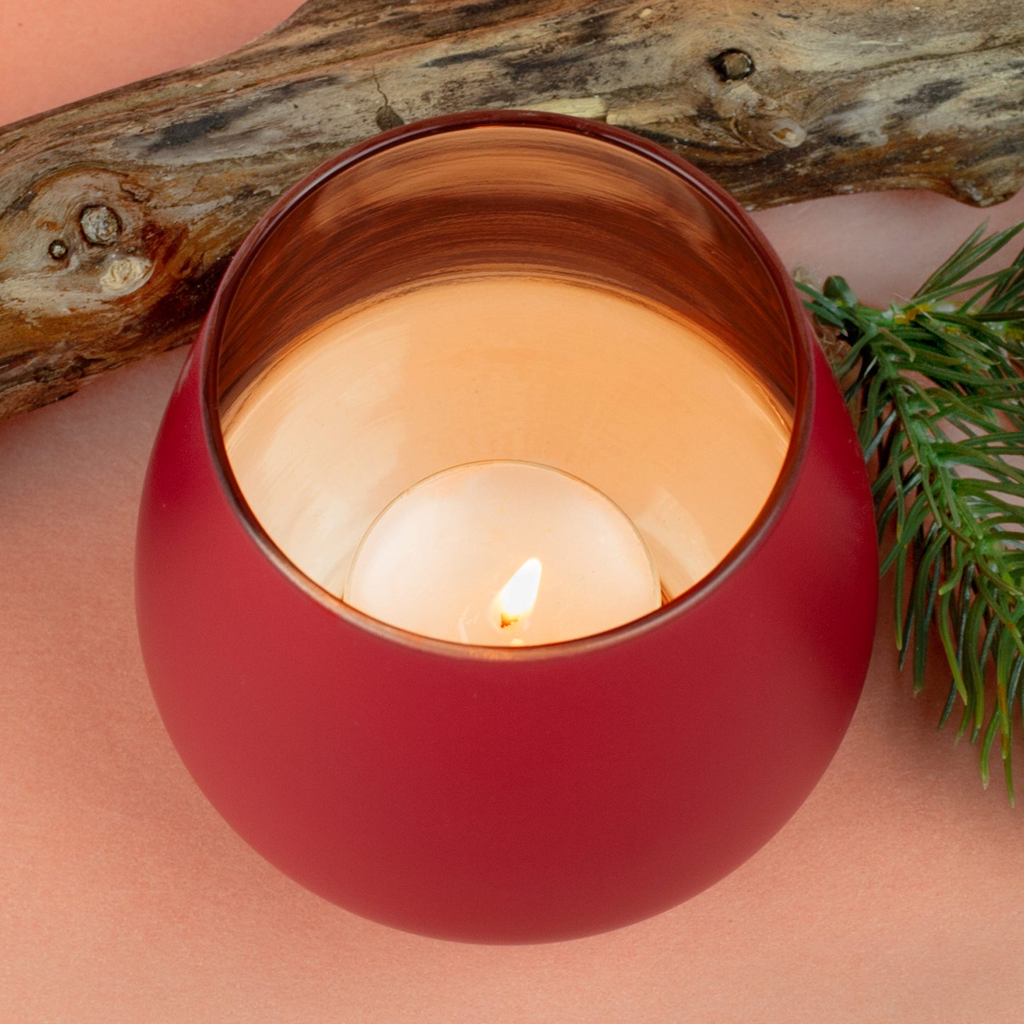 Nahaufnahme der kupferfarbenen Innenfläche eines Windlichts mit Kerze und warmem Lichtschein