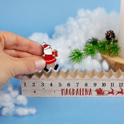Detailansicht des Adventskalenders mit Name „Magdalena“, während die bewegliche Weihnachtsmann-Figur auf der Holzleiste versetzt wird
