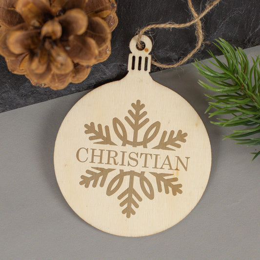 Detailansicht des Schneeflockenmotivs mit graviertem Namen auf dem Weihnachtsanhänger aus Holz.