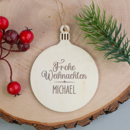 Holzanhänger Kugel mit Gravur „Frohe Weihnachten Michael“, auf Holzscheibe mit Beeren und Tannenzweig dekoriert.