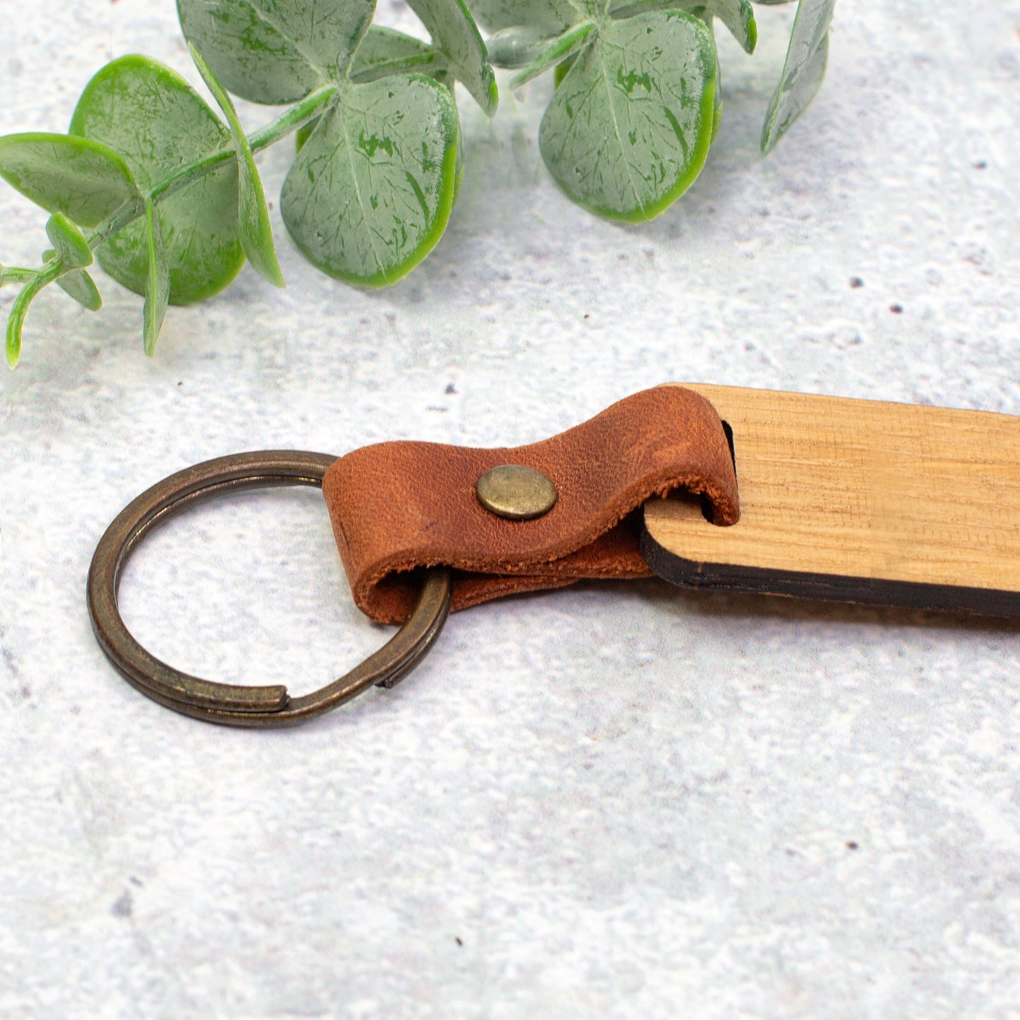 Detailaufnahme vom braunen Lederband und Metallring des handgefertigten Schlüsselanhängers aus Holz