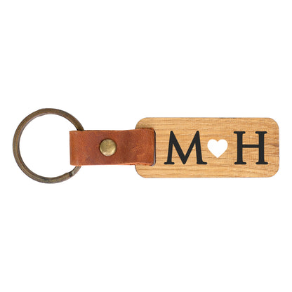 Freisteller von personalisiertem Schlüsselanhänger aus Holz mit Initialen M und H und Herzmotiv