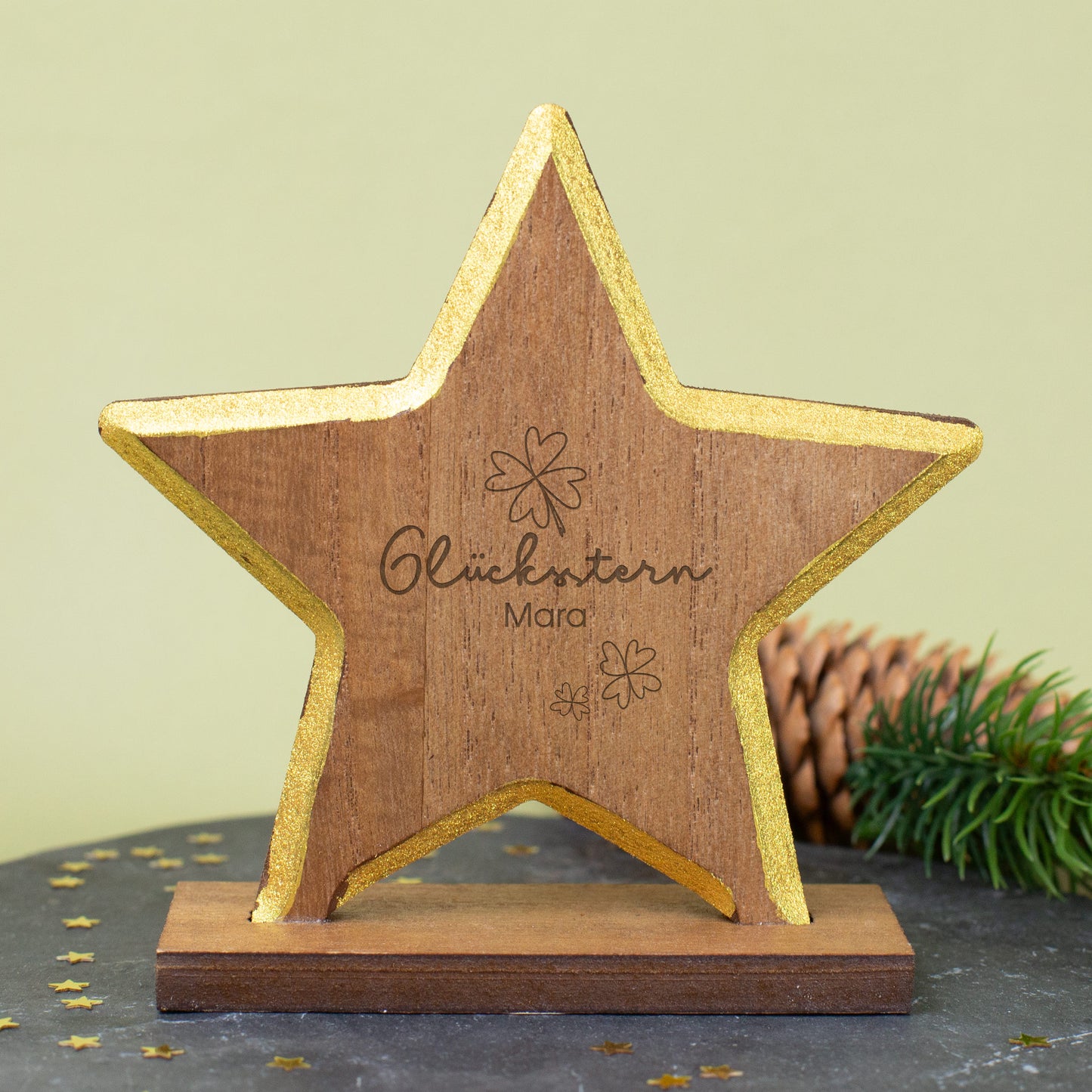 Nahaufnahme des gravierten Glückssterns mit Goldrand, Kleeblättern und Namensgravur auf Holz