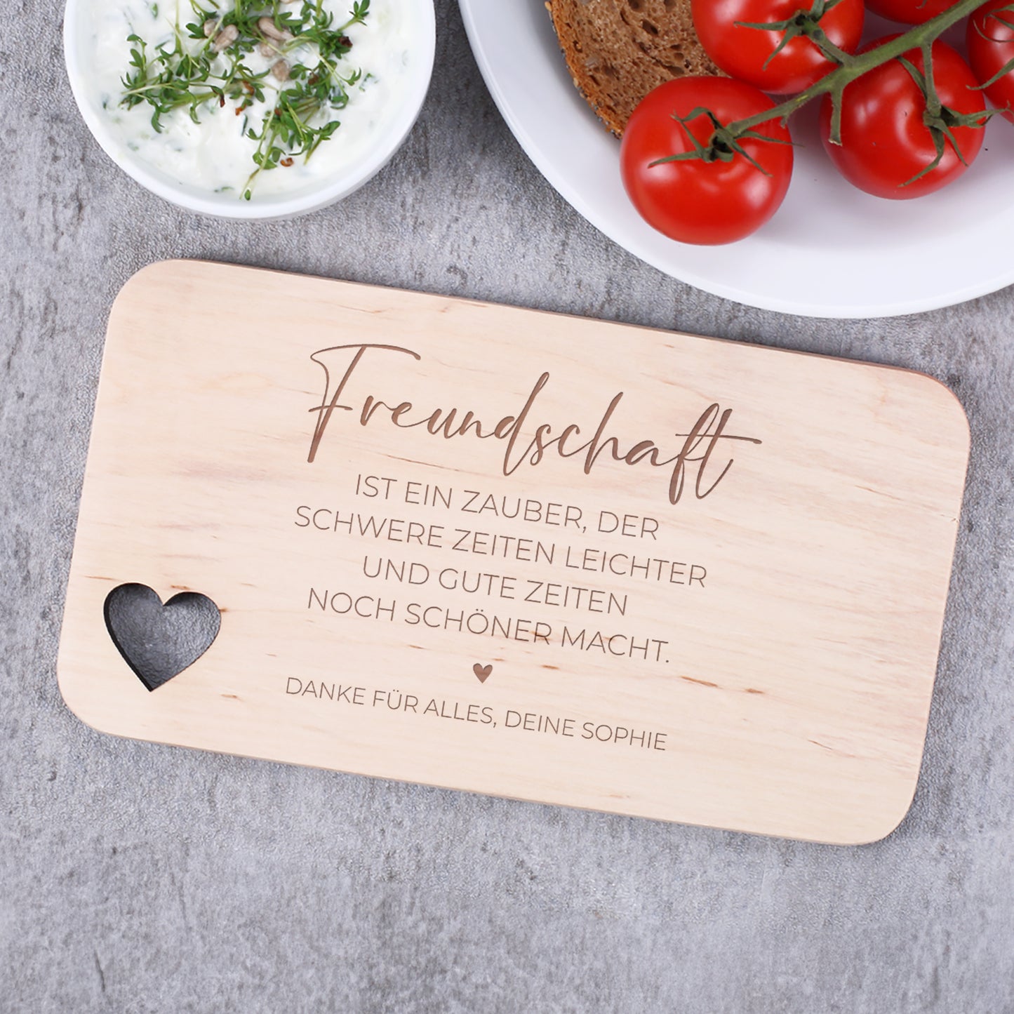 Graviertes Holzbrettchen mit dem Spruch über Freundschaft und personalisierter Widmung – dekoriert mit Brot, Tomaten und Dip