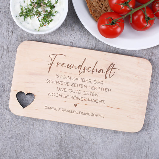 Graviertes Holzbrettchen mit dem Spruch über Freundschaft und personalisierter Widmung – dekoriert mit Brot, Tomaten und Dip