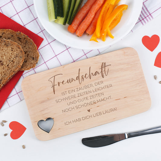 Frühstücksbrettchen mit Freundschaftsspruch, Gravurtext „Ich hab dich lieb Laura!“ und Gemüse auf einem gedeckten Tisch