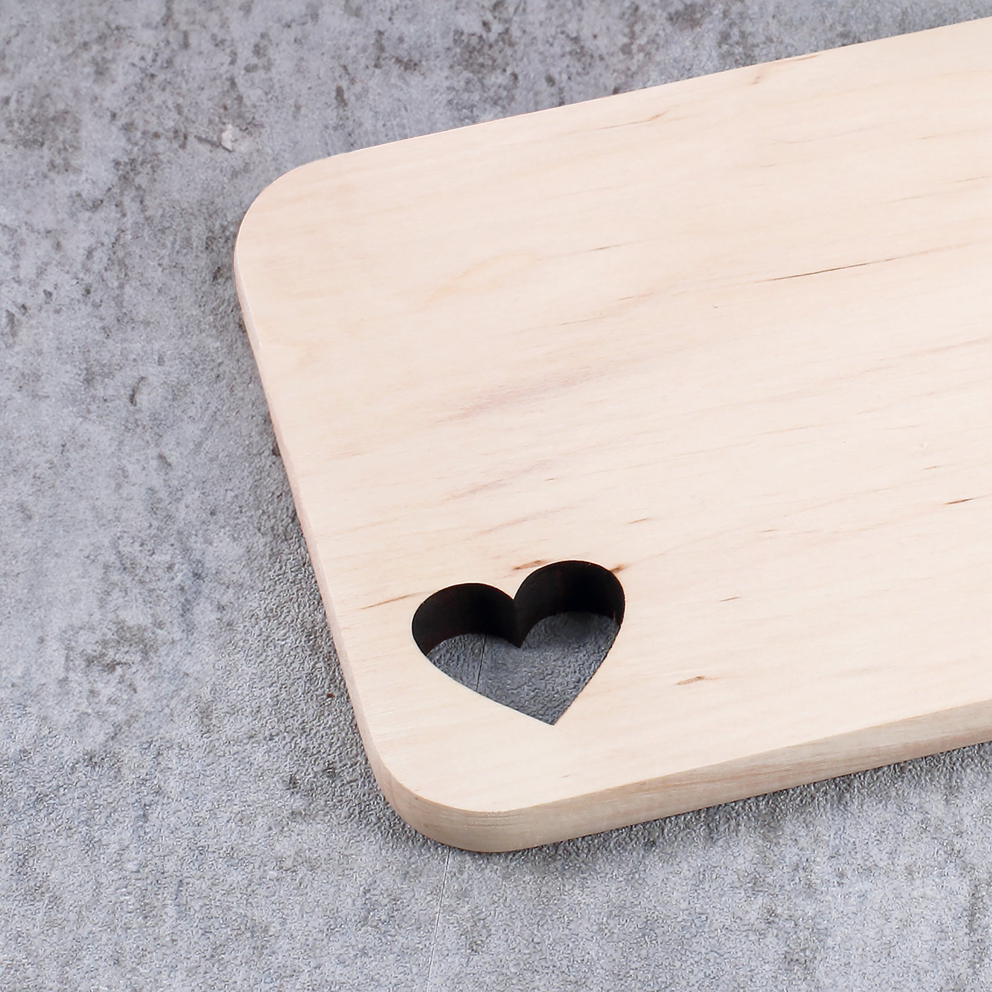 Nahaufnahme des gravierten Erlenholz-Brettchens mit ausgestanztem Herzmotiv in der Ecke