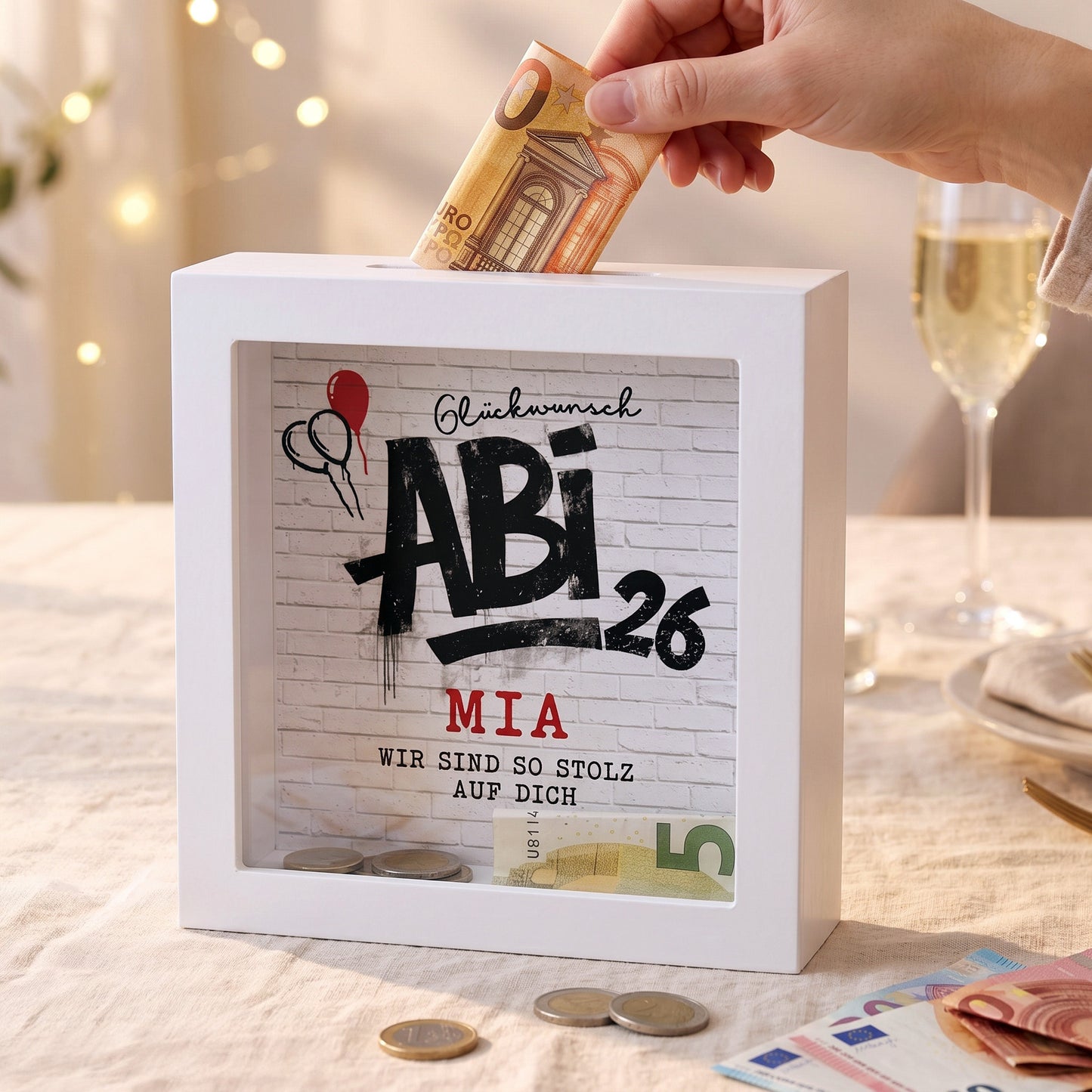 Personalisierte Abi 2026 Spardose mit Name Mia auf festlich gedecktem Tisch und Geldschein