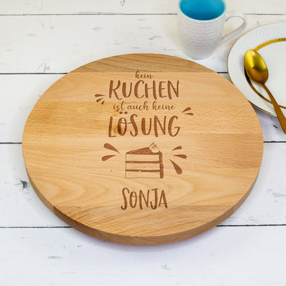 Holz-Tortenplatte mit Gravur „Kein Kuchen ist auch keine Lösung – Sonja“ auf weiß gedecktem Tisch