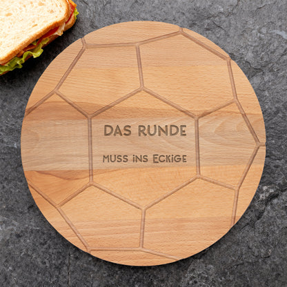Fußball-Holzbrett mit Gravur „DAS RUNDE MUSS INS ECKIGE“ und Sandwich daneben