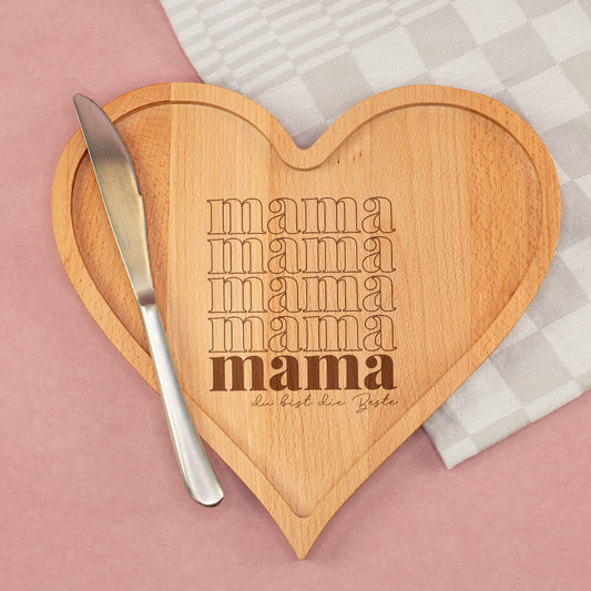 Herz Holzbrettchen mit Mama Schriftzug und individueller Gravur auf Tisch mit Messer und Stoff