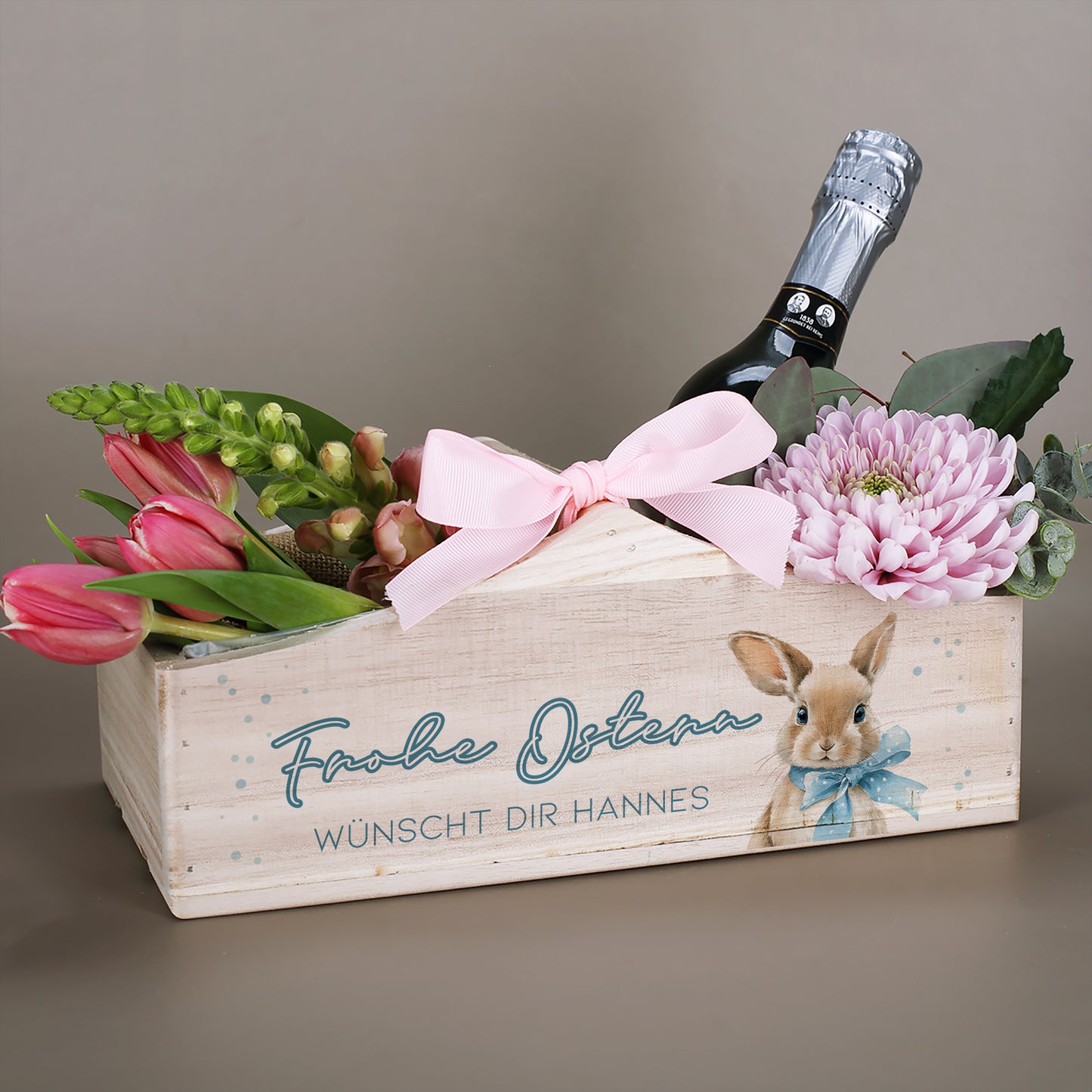 Holz Geschenkkorb zu Ostern mit Blumen, Flasche, Hasenmotiv und Wunschtext als personalisierte Osterkiste
