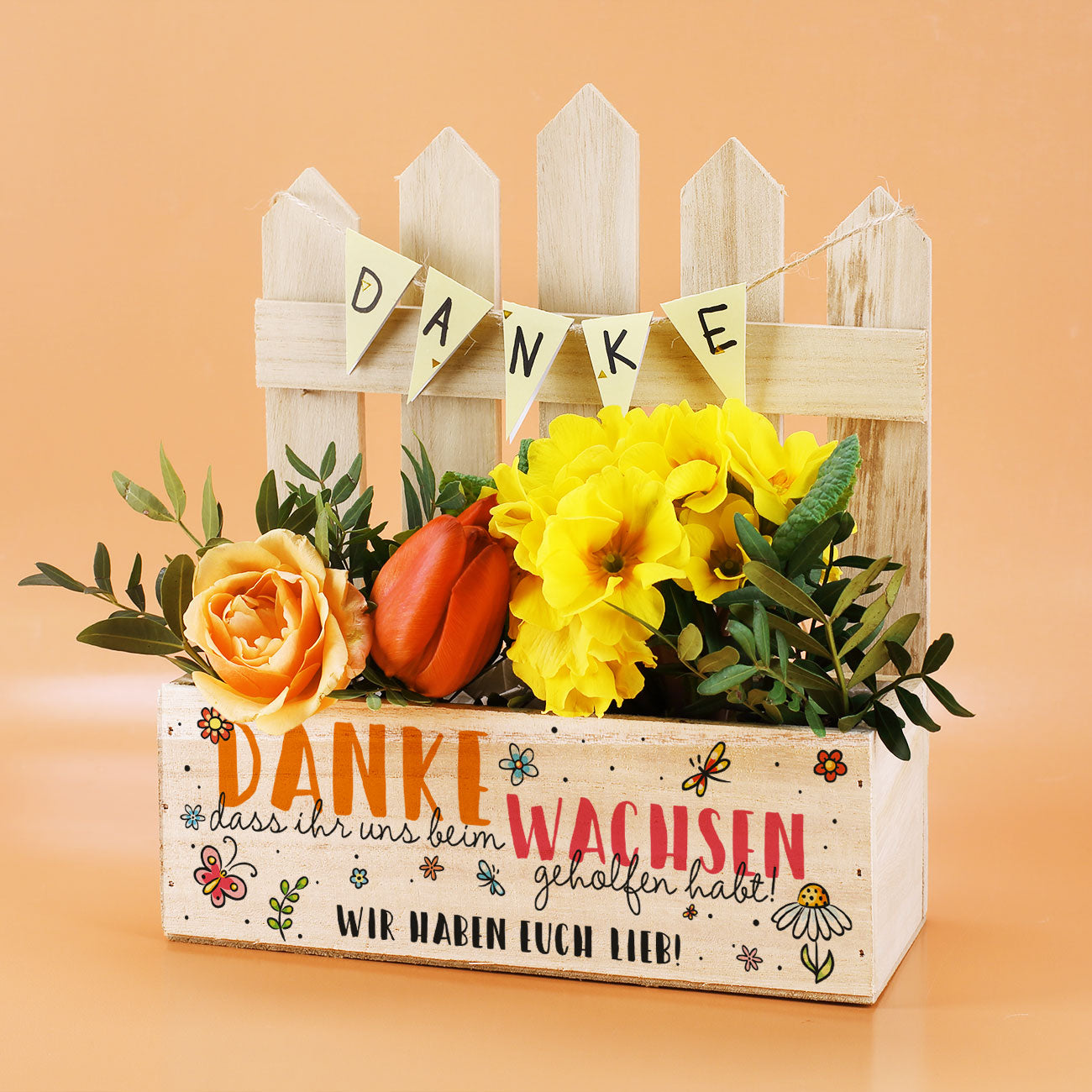 Pflanzkiste mit Zaun und Blumen, Text „Danke, dass ihr uns beim Wachsen geholfen habt“ und Wunschtext „Wir haben euch lieb!“