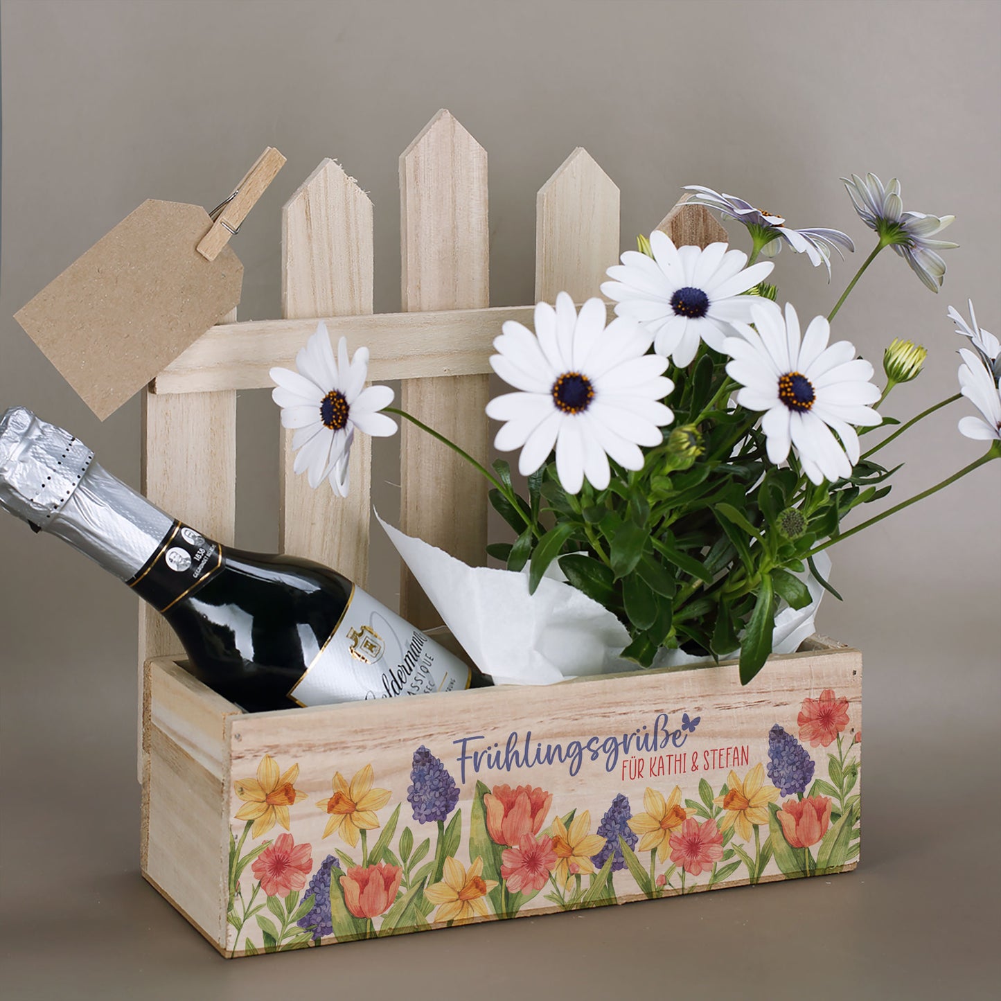 Geschenkkorb mit Zaun-Rückwand Frühlingsgrüße mit Wunschtext befüllt mit Blumen und Sekt