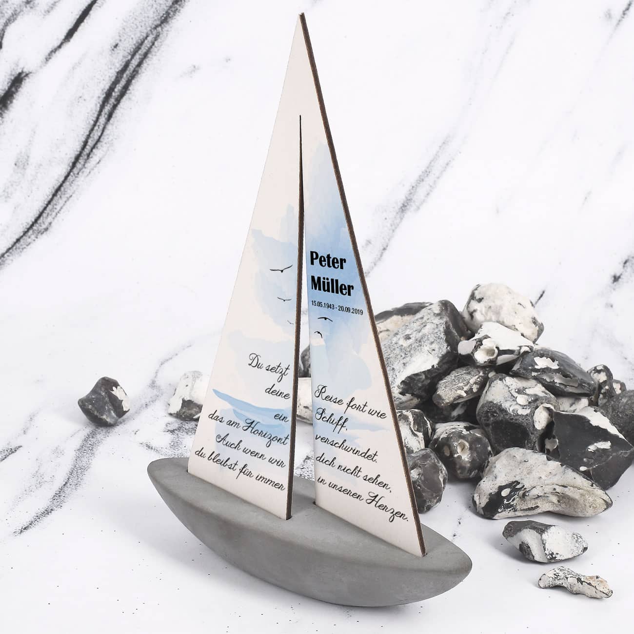 Segelboot mit Trauerspruch und Name des Verstorbenen mit Datum aufgedruckt auf dem Segel des Schiffs