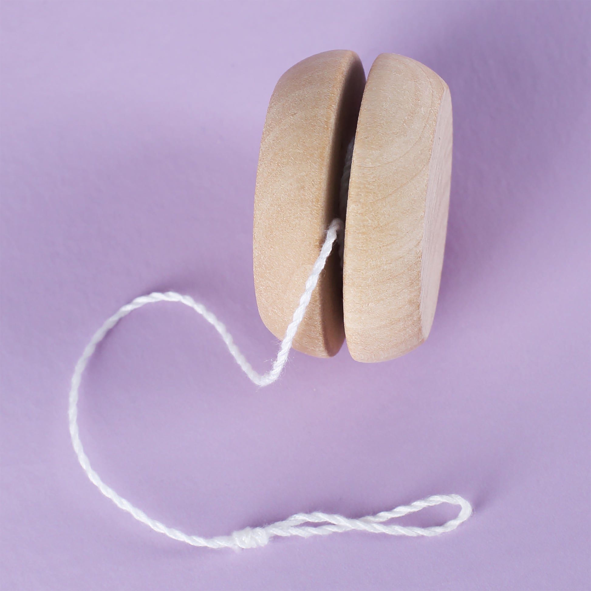Seitenansicht des naturfarbenen Holz-Yo-Yos auf lila Untergrund