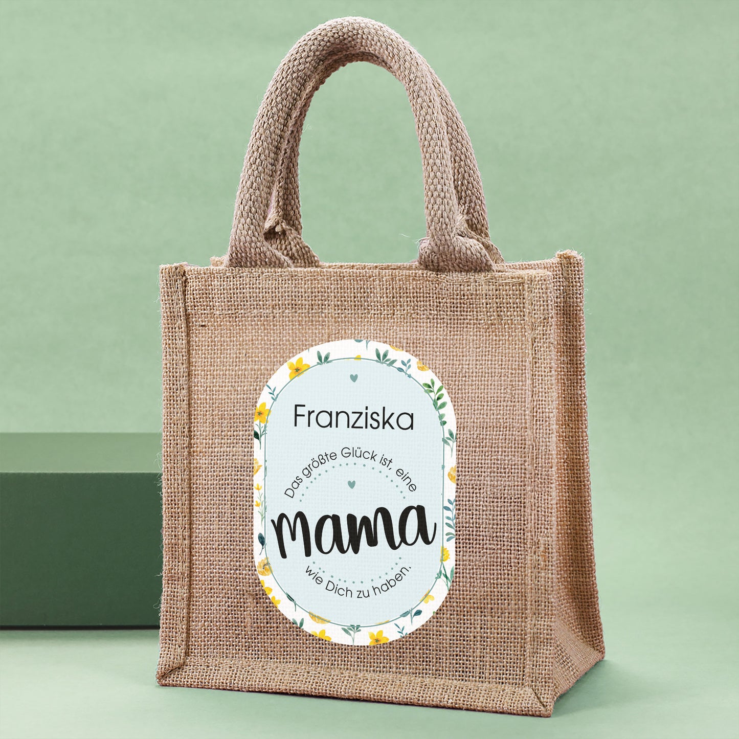 Personalisierbare Jute-Geschenktasche für Mama seitlich fotografiert auf grünem Hintergrund