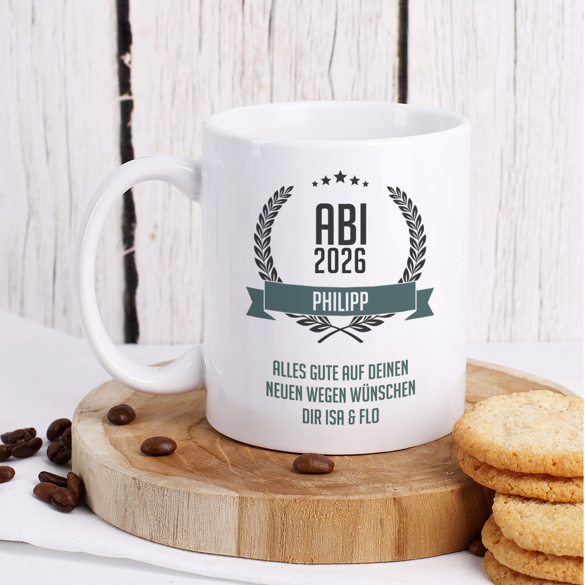 Glückwunsch-Tasse zum Abitur mit Name "Philipp" und Wunschtext dekoriert auf Baumscheibe mit Keksen und Kaffeebohnen