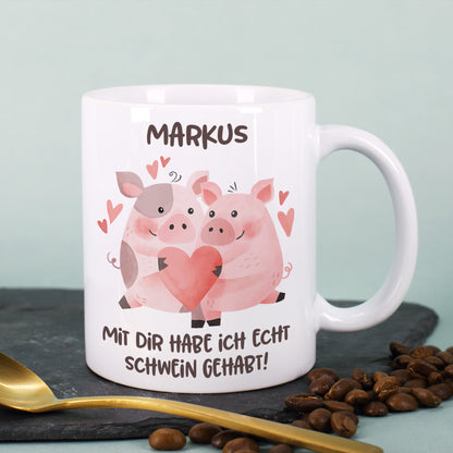 Tasse mit Schweinchen-Motiv und Name „Markus“, daneben Kaffeebohnen und goldener Löffel
