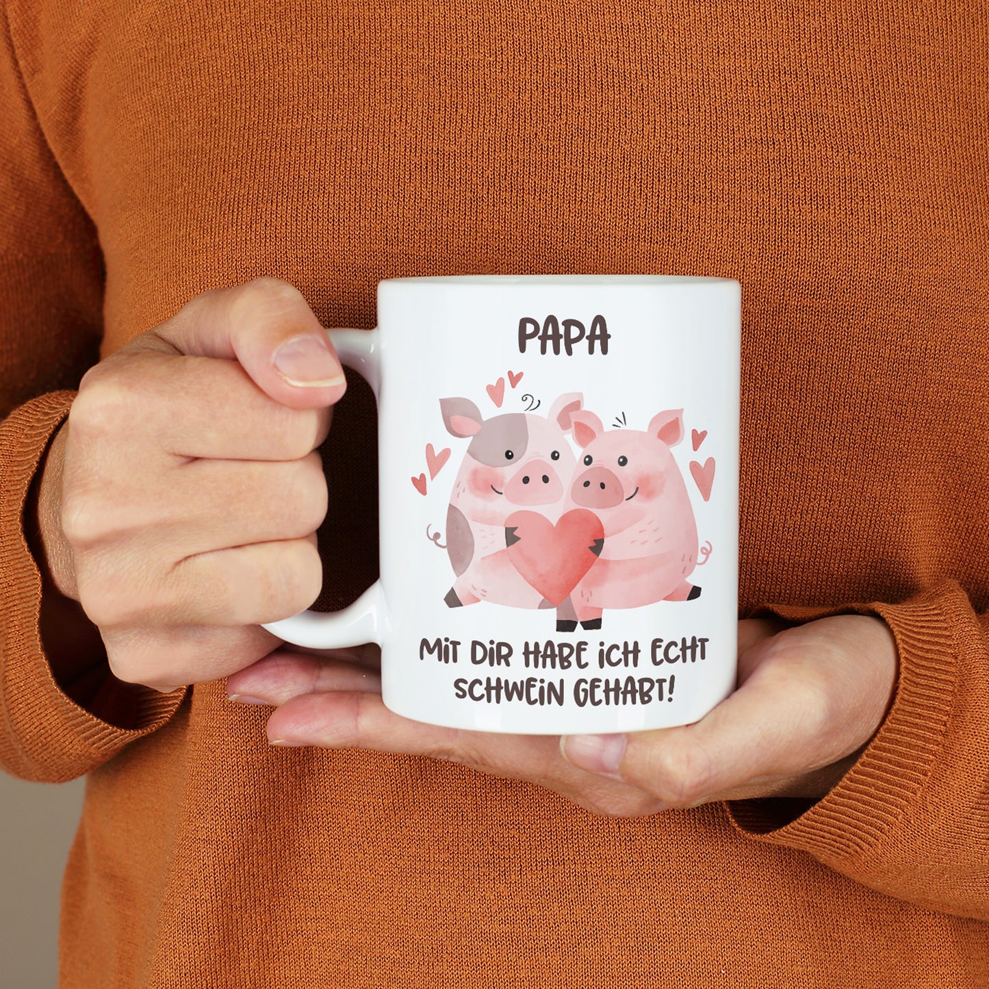 Person hält Tasse mit Schweinchen-Motiv und Name „Papa“ in der Hand