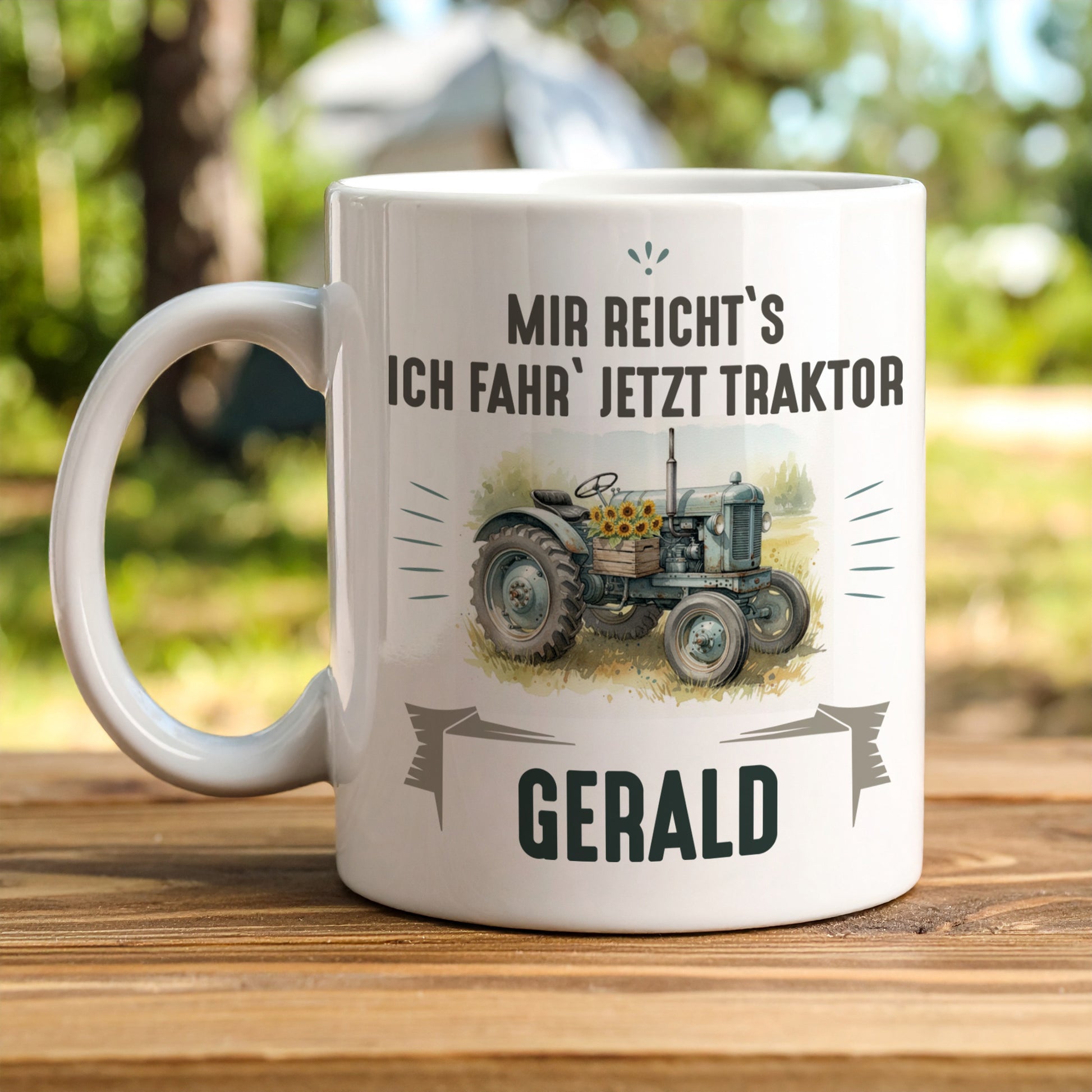 Retro-Traktor-Tasse mit Aufschrift „Mir reicht’s, ich fahr’ jetzt Traktor“ und Name Gerald, auf Holztisch im Freien