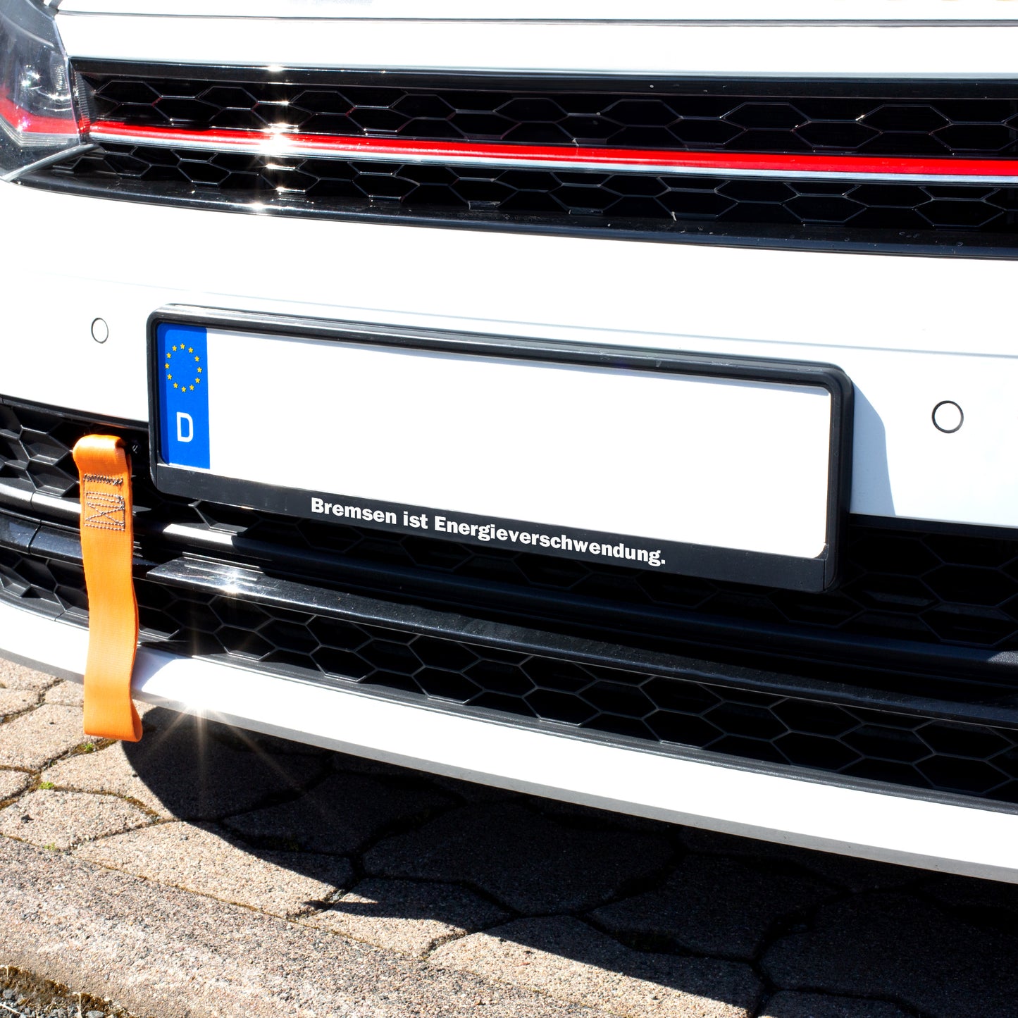 Schwarzer Kennzeichenhalter am Auto mit individuellem Spruch „Bremsen ist Energieverschwendung“