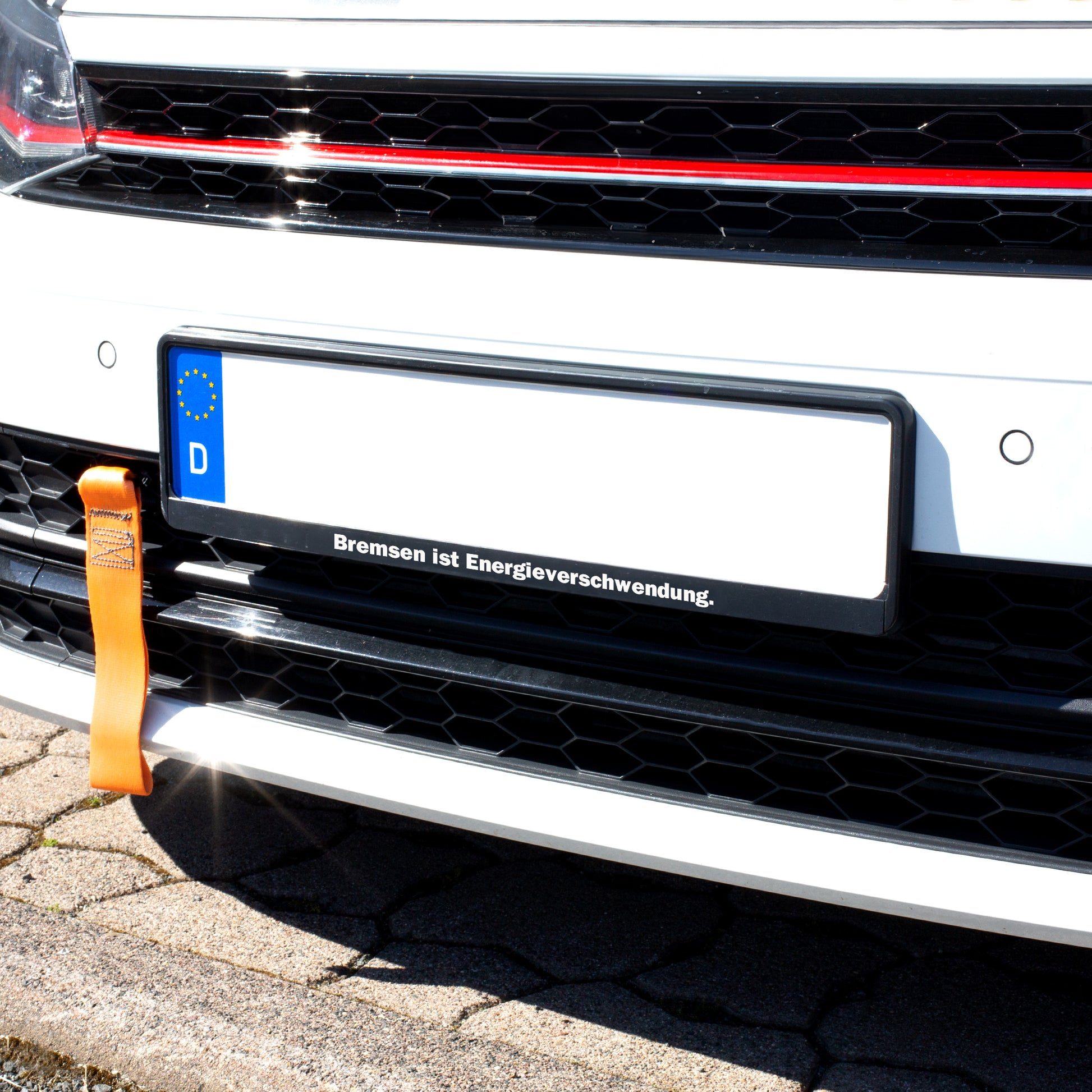 Schwarzer Kennzeichenhalter am Auto mit individuellem Spruch „Bremsen ist Energieverschwendung“