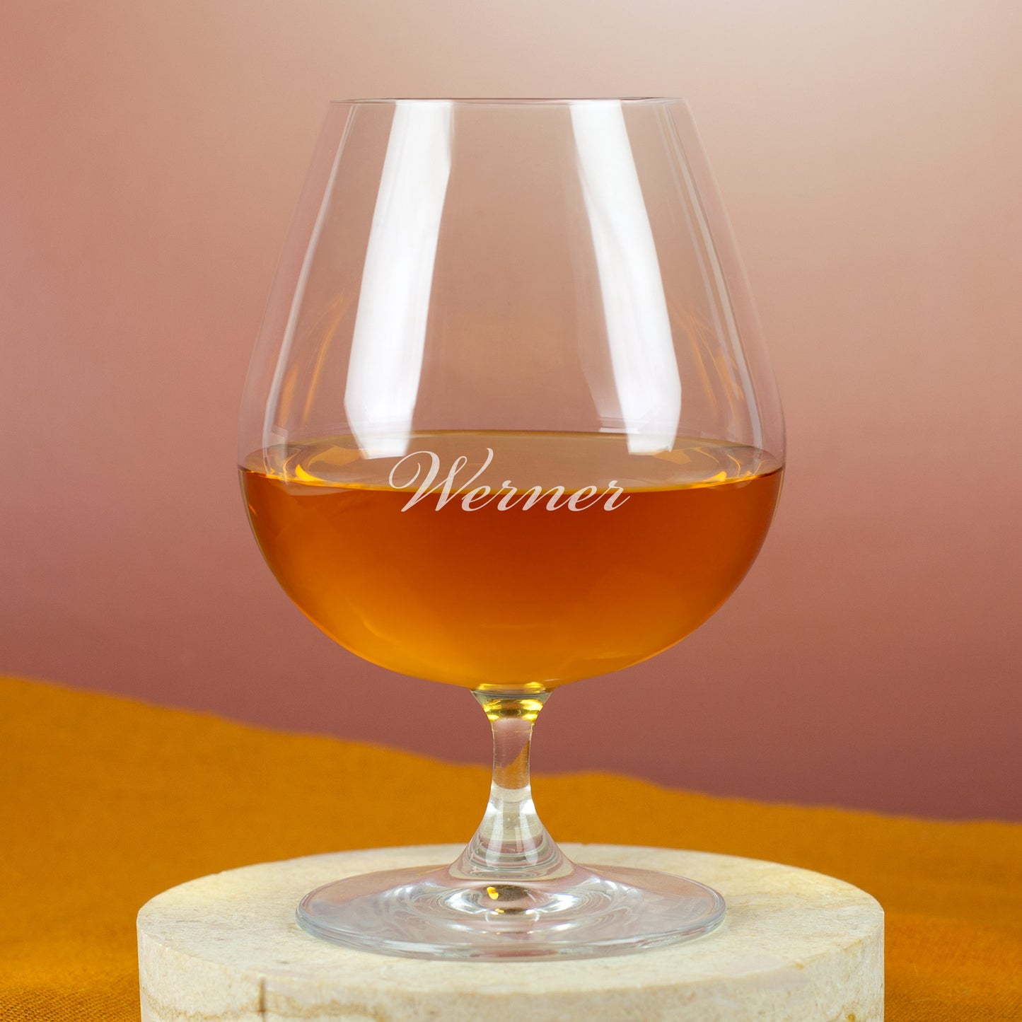 Leonardo Cognacschwenker mit Gravur „Werner“ – gefüllt mit goldbraunem Cognac, auf hellem Steinuntergrund.