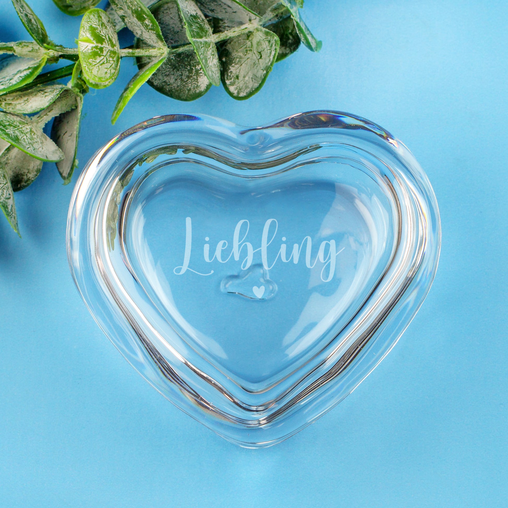 Leonardo Glas-Herzdose mit Gravur Liebling und Herzsymbol auf hellblauem Hintergrund mit Eukalyptus