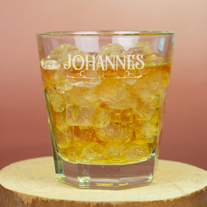 Leonardo-Trinkglas mit Gravur von Name und Ornamentmotiv, gefüllt mit Getränk und Eiswürfeln auf Holzuntergrund